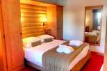 Cozy up in this charming bedroom featuring a warm wooden interior and a comfortable bed.