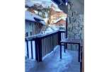 Experience the charm of a winter wonderland from this property's balcony, offering stunning views of a snow-covered village nestled in the mountains.