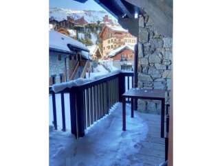 Experience the charm of a winter wonderland from this property's balcony, offering stunning views of a snow-covered village nestled in the mountains.