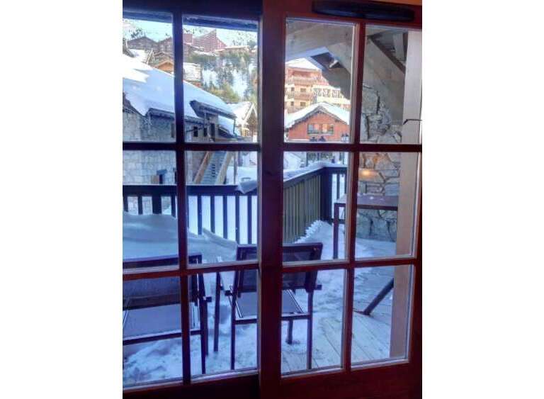 Experience the charm of a winter wonderland from this property's balcony, offering stunning views of snow-covered chalets and a picturesque mountain village.