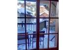 Experience the charm of a winter wonderland from this property's balcony, offering stunning views of snow-covered chalets and a picturesque mountain village.
