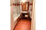 This charming bathroom features a classic white bathtub with a shower, complemented by warm wooden accents.