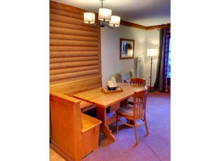 Enjoy cozy meals in this charming dining nook featuring a wooden banquette and a matching table.