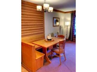 Enjoy cozy meals in this charming dining nook featuring a wooden banquette and a matching table.