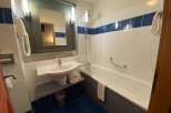 This bathroom features a clean and modern design with white tiles and a blue accent stripe.