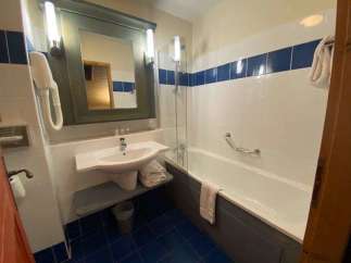 This bathroom features a clean and modern design with white tiles and a blue accent stripe.