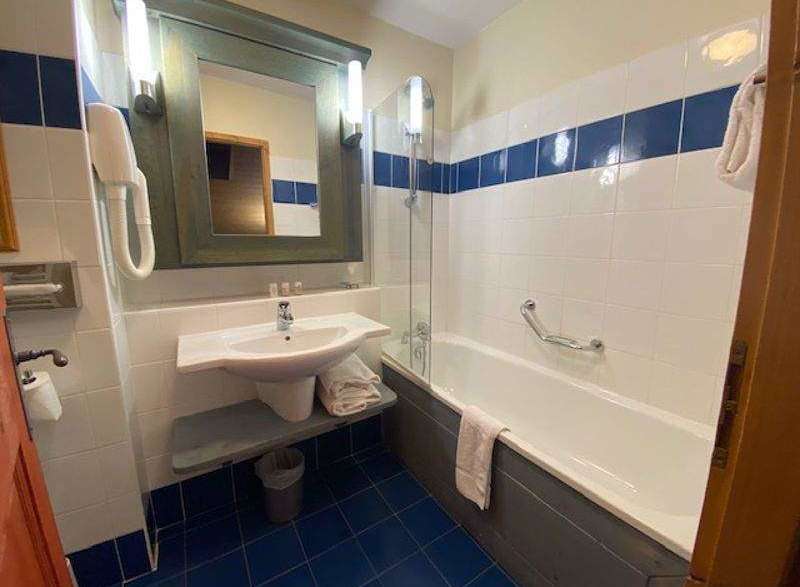 This bathroom features a clean and modern design with white tiles and a blue accent stripe.