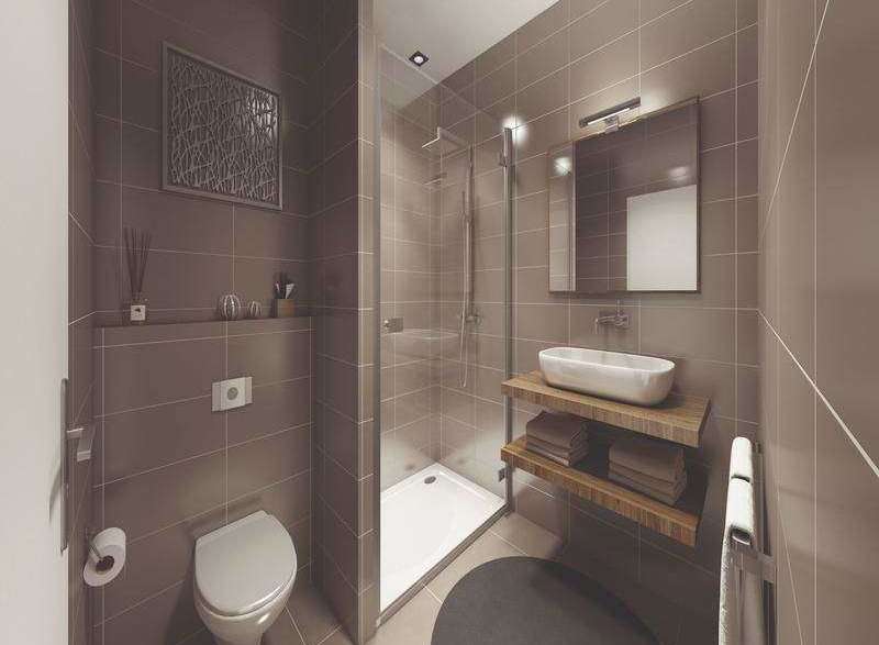 This modern bathroom features sleek, neutral-toned tiles and a minimalist design.