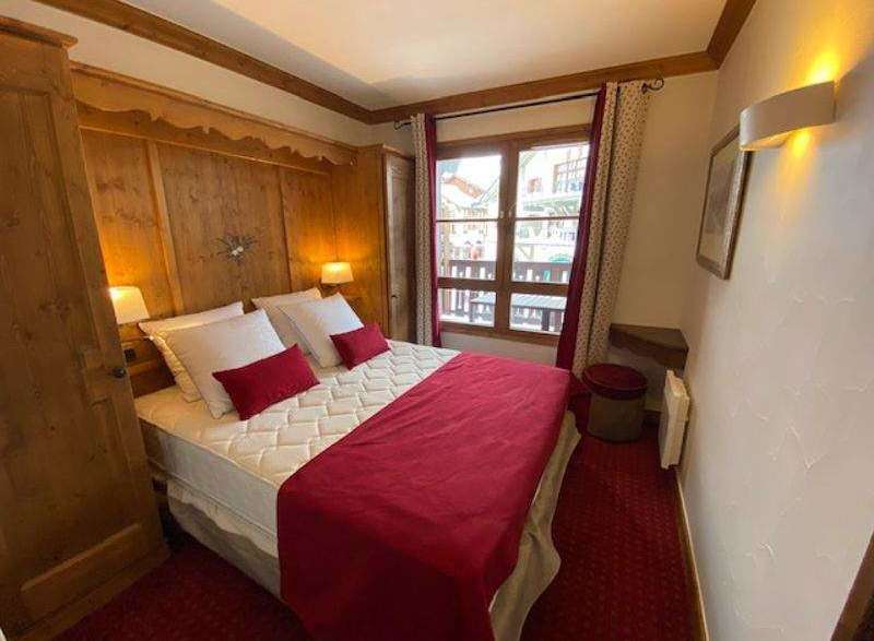 Cozy bedroom with a comfortable bed and a vibrant red comforter.