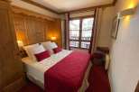 Cozy bedroom with a comfortable bed and a vibrant red comforter.