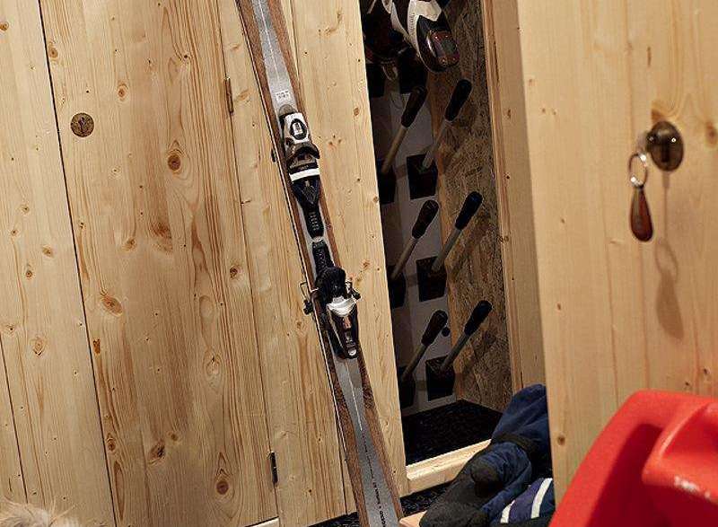 Cozy ski storage room with wooden paneling.