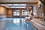 Relax and unwind in this luxurious indoor pool, surrounded by rustic wooden beams and a stone accent wall.