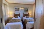 Cozy twin bedroom featuring two comfortable beds with warm bedding, perfect for a relaxing stay.