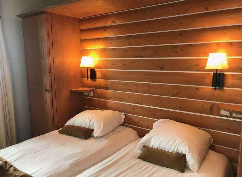 Cozy up in this charming bedroom featuring a rustic wooden headboard and two comfortable beds.