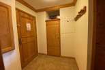 Step into this inviting entryway, featuring warm wooden doors and a practical coat rack.