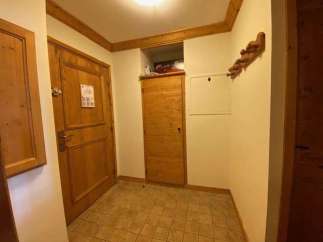 Step into this inviting entryway, featuring warm wooden doors and a practical coat rack.