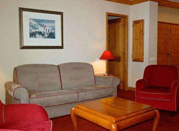 Cozy up in this inviting living space, featuring a comfortable sofa and a charming red armchair.