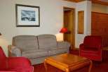 Cozy up in this inviting living space, featuring a comfortable sofa and a charming red armchair.