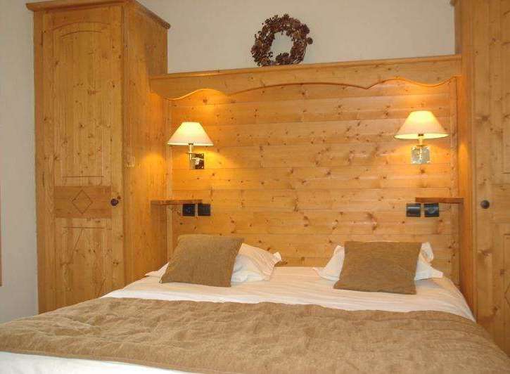 Cozy bedroom with wooden paneling and matching furniture.