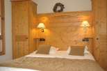 Cozy bedroom with wooden paneling and matching furniture.