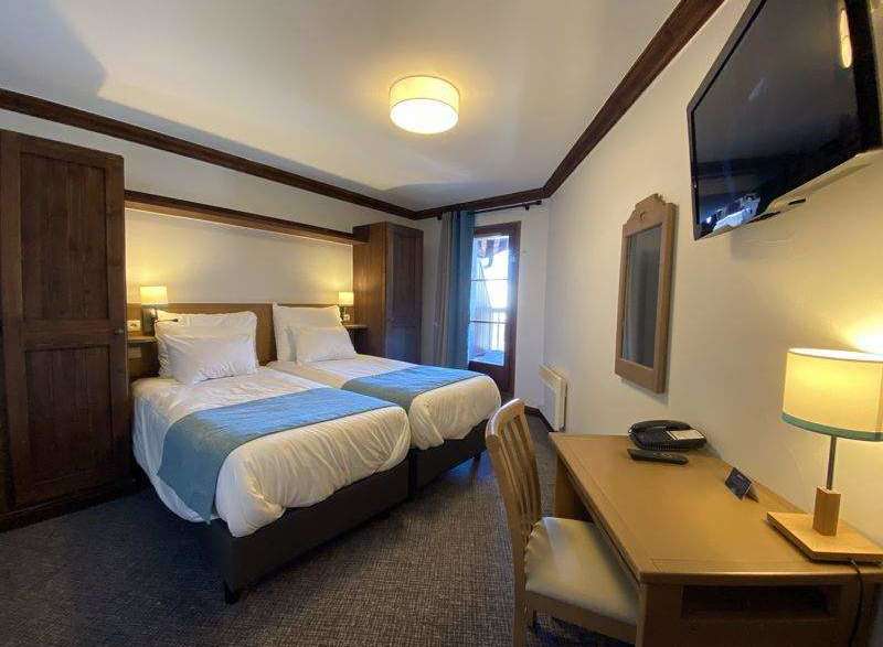 Cozy hotel room featuring two twin beds with crisp white linens and a calming blue accent.