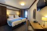 Cozy hotel room featuring two twin beds with crisp white linens and a calming blue accent.