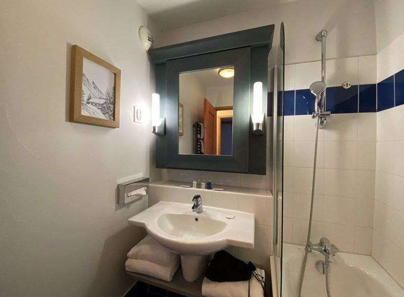 This charming bathroom features a stylish vanity with a sleek sink and a well-lit mirror.