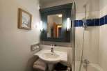 This charming bathroom features a stylish vanity with a sleek sink and a well-lit mirror.