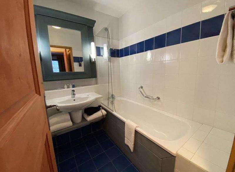 This bathroom features a modern design with a sleek white bathtub and a stylish blue tile floor.