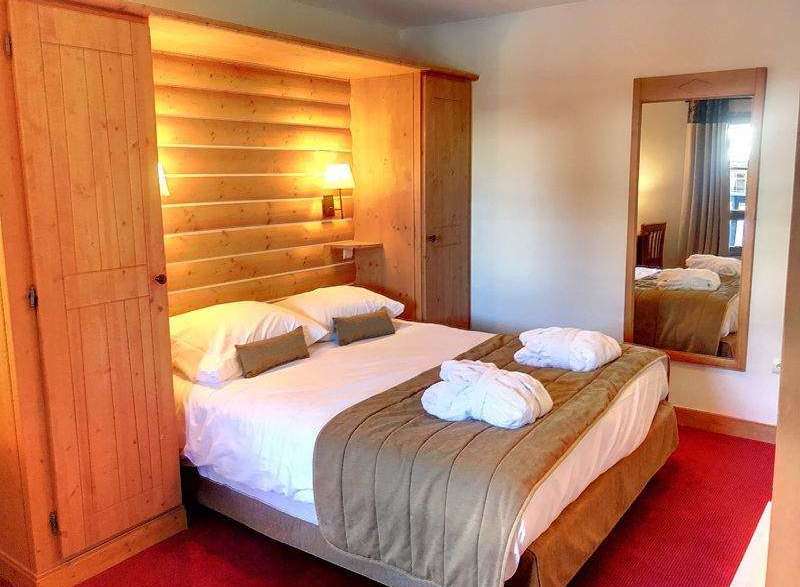 Cozy up in this charming bedroom featuring a warm wooden interior and a comfortable bed.
