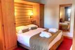 Cozy up in this charming bedroom featuring a warm wooden interior and a comfortable bed.