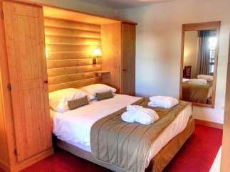 Cozy up in this charming bedroom featuring a warm wooden interior and a comfortable bed.