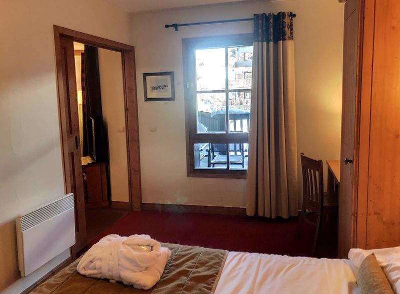 Cozy hotel room featuring a comfortable bed with a plush robe, perfect for relaxation.