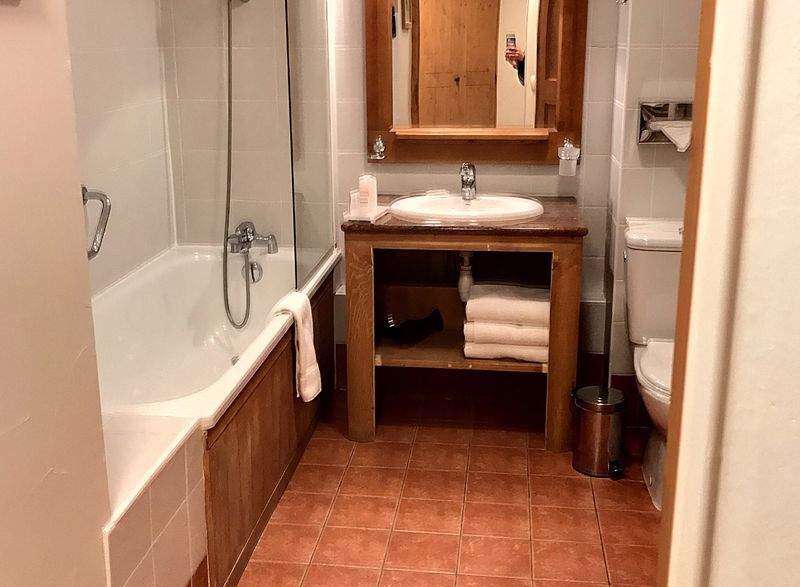 This charming bathroom features a cozy ambiance with its warm-toned tiles and wooden accents.