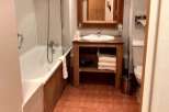 This charming bathroom features a cozy ambiance with its warm-toned tiles and wooden accents.