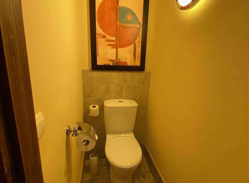 This cozy bathroom features a modern toilet and a stylish painting, creating a comfortable and inviting space.
