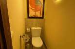 This cozy bathroom features a modern toilet and a stylish painting, creating a comfortable and inviting space.