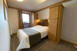 Cozy bedroom with a comfortable bed and a stylish wooden wardrobe.