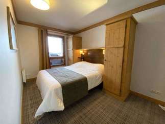 Cozy bedroom with a comfortable bed and a stylish wooden wardrobe.