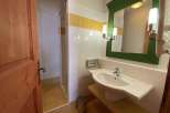 This charming bathroom features a bright and airy design with a modern sink and a stylish green-framed mirror.