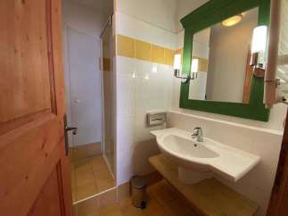 This charming bathroom features a bright and airy design with a modern sink and a stylish green-framed mirror.