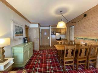 This charming property features a cozy living space with a rustic wooden dining set, perfect for enjoying meals.