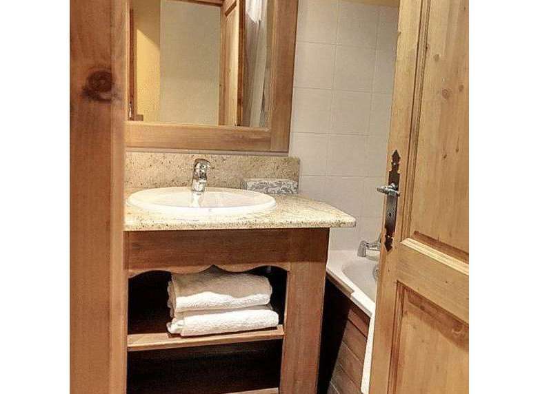 This charming bathroom features a rustic wooden vanity with ample storage for towels and toiletries.