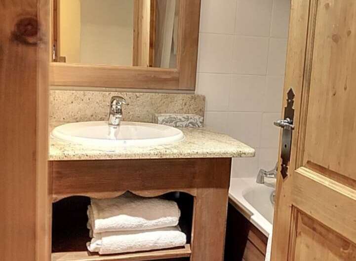 This charming bathroom features a rustic wooden vanity with a granite countertop and a built-in sink.