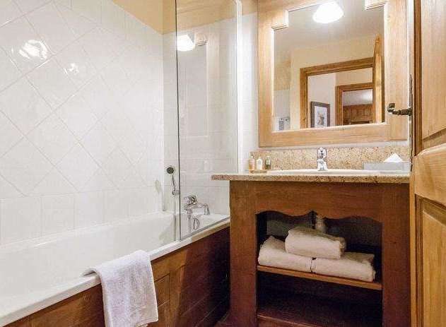 This charming bathroom features a classic design with wooden accents and a bright, inviting atmosphere.