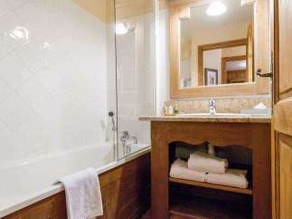 This charming bathroom features a classic design with wooden accents and a bright, inviting atmosphere.