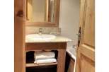 This charming bathroom features a rustic wooden vanity with ample storage for towels and toiletries.
