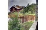 Experience mountain living in this stunning property featuring a charming wooden fence and lush greenery.