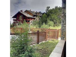 Experience mountain living in this stunning property featuring a charming wooden fence and lush greenery.