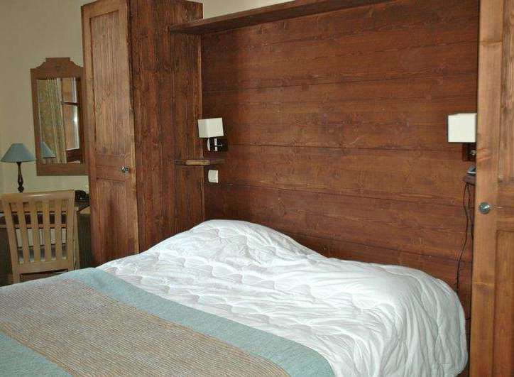 This cozy bedroom features a rustic wooden headboard and matching wardrobe, creating a warm and inviting atmosphere.
